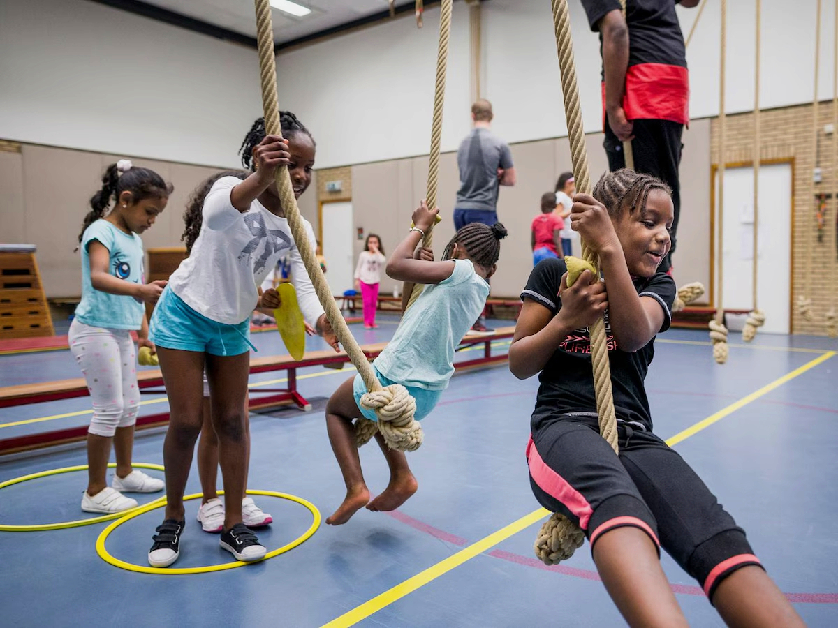 Kinderen doen mee aan een begeleide gymactiviteit met klimtouwen